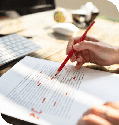 A person with a red pencil reviews a manuscript line by line.