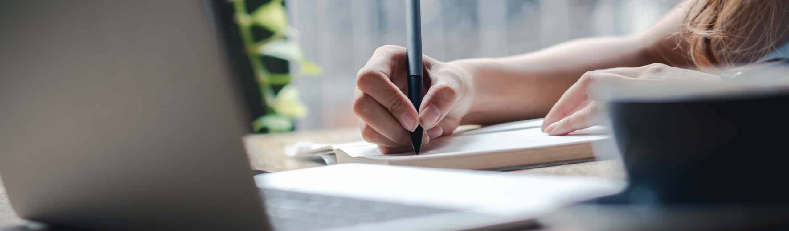 Hand holding pen and writing on paper.Listing on paper concept.
